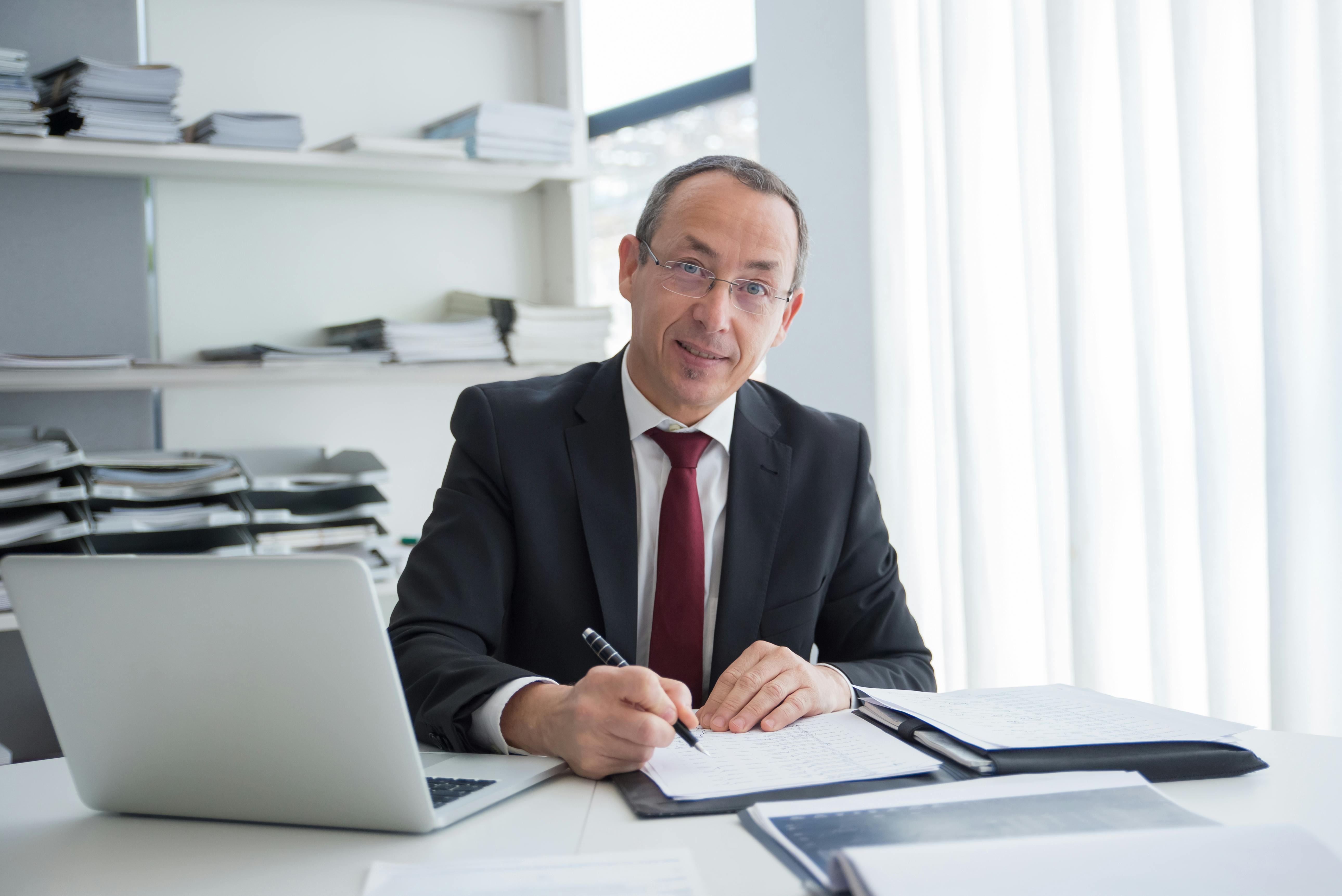 Ein Team von Experten diskutiert an einem Tisch mit Laptops und digitalen Geräten über KI-Software für den Mittelstand.