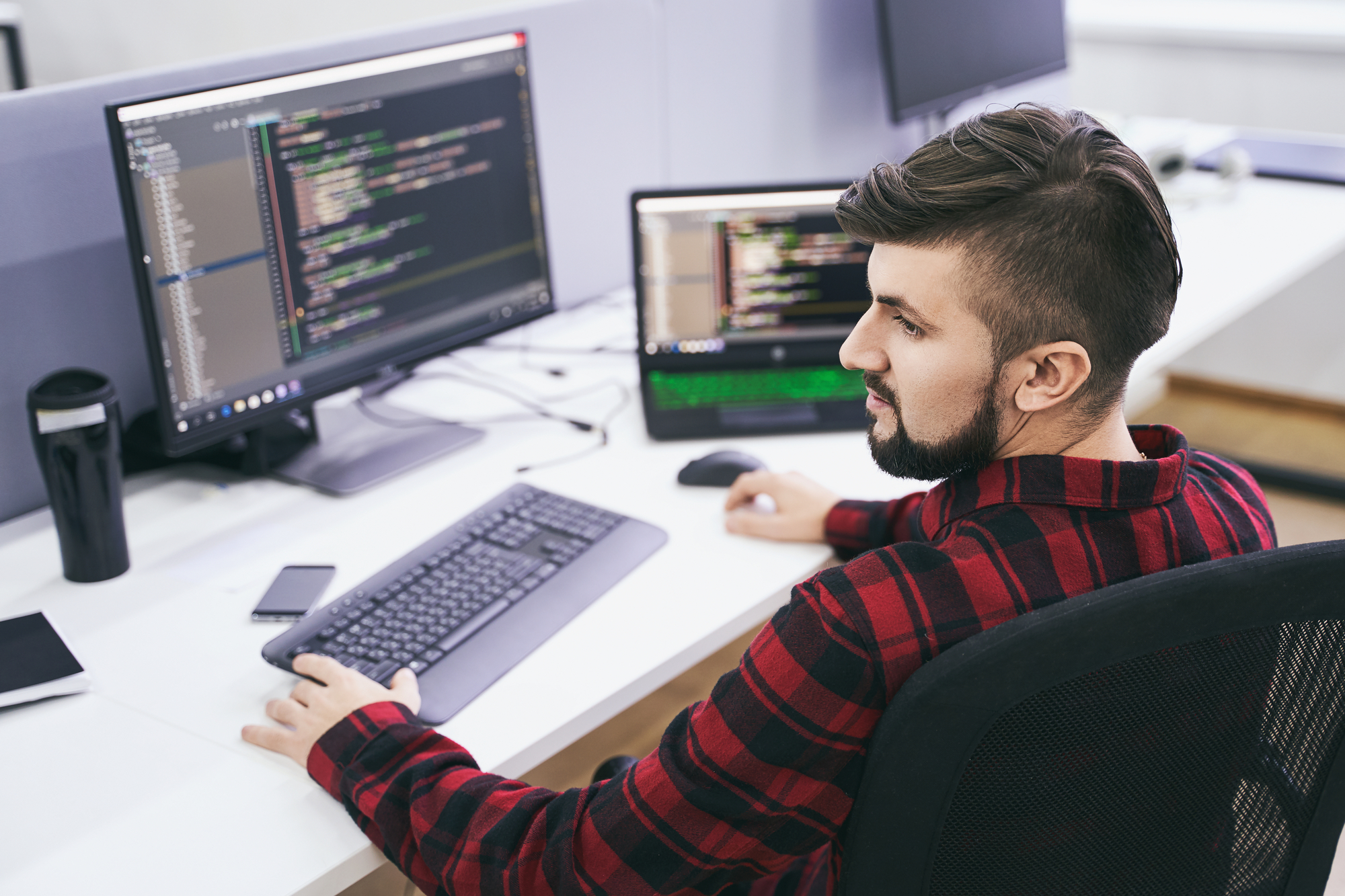 Eine Person überprüft Daten und Diagramme auf einem Computerbildschirm, um die Qualitätskontrolle von KI-Systemen zu gewährleisten.